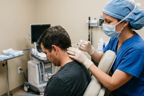 Médico realizando bloqueio do nervo occipital em paciente com enxaqueca