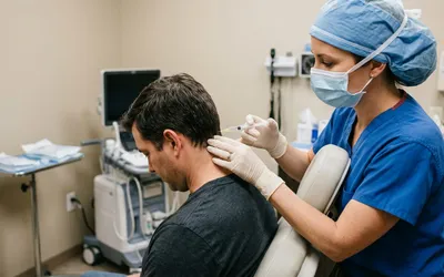 Médico realizando bloqueio do nervo occipital em paciente com enxaqueca